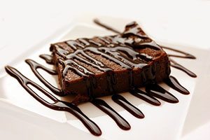 A chocoalte borwnie on a plate with a fudge drizzle